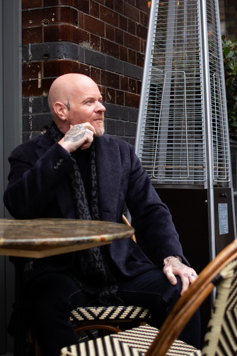 Carl Reader, dark coat, cafe table