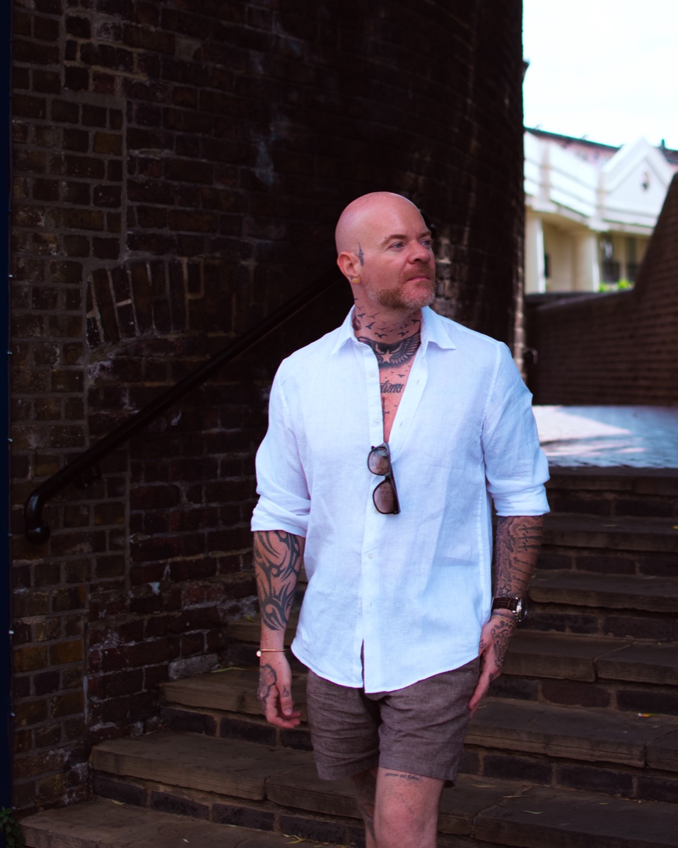 Carl Reader, white linen shirt, brown shorts, brick steps