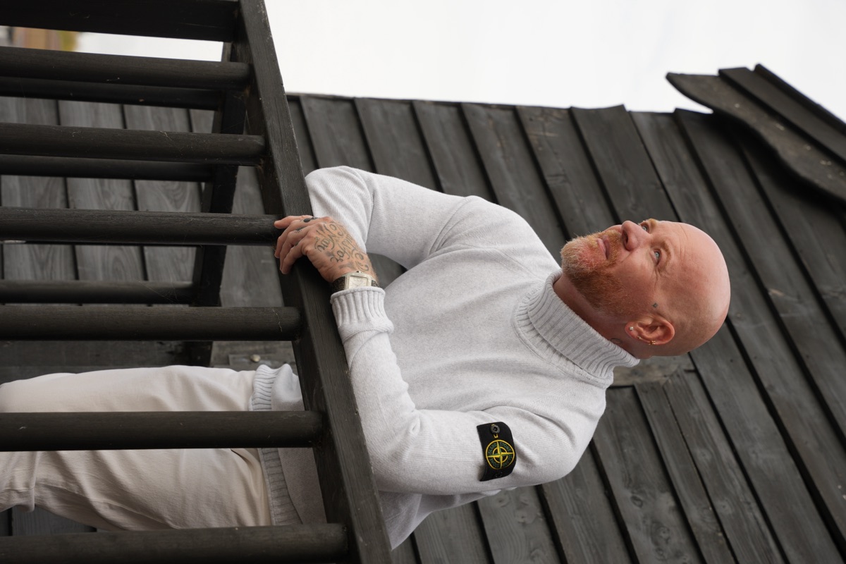 Carl Reader, cream rollneck Stone Island jumper, dark balcony