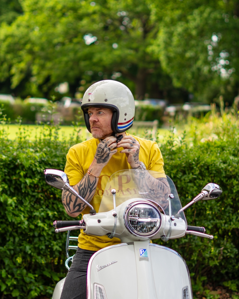 Carl Reader, yellow tee, on a Vespa scooter